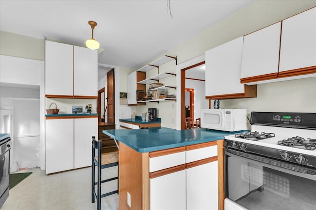 kitchen featuring gas stove, white cabinets, and kitchen peninsula