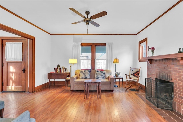 living room with ornamental molding, hardwood / wood-style floors, ceiling fan, and a fireplace