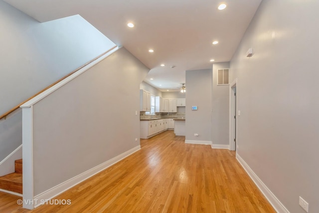 unfurnished living room featuring ceiling fan, light hardwood / wood-style flooring, and sink