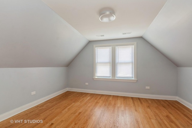 bonus room with vaulted ceiling and light wood-type flooring