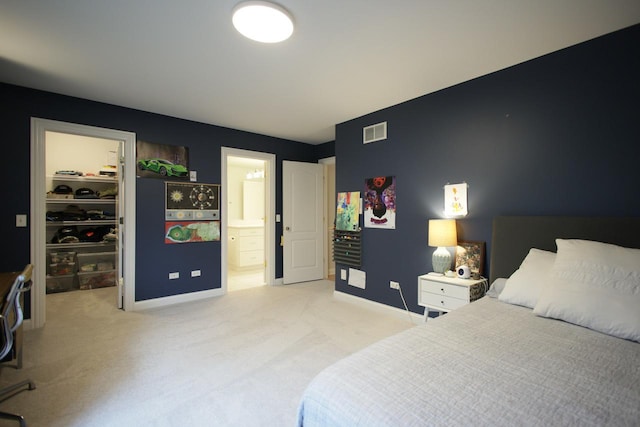 carpeted bedroom featuring a spacious closet, a closet, and ensuite bath