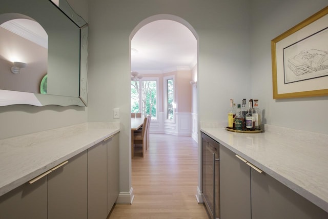 interior space with gray cabinetry, crown molding, beverage cooler, and light hardwood / wood-style flooring