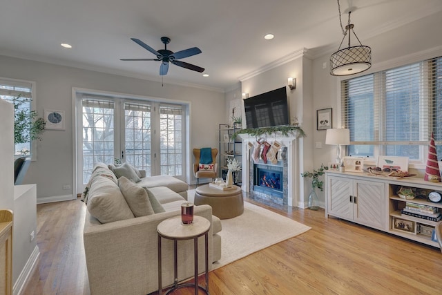 living room featuring plenty of natural light, ceiling fan, light wood-type flooring, and ornamental molding