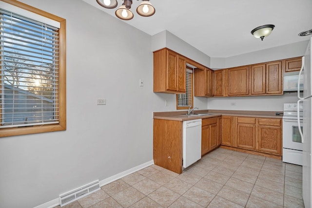 kitchen featuring light tile patterned floors, white appliances, and sink