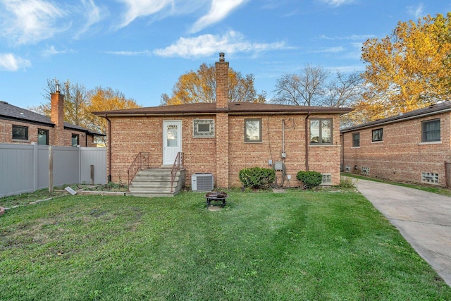 rear view of house featuring central air condition unit and a lawn