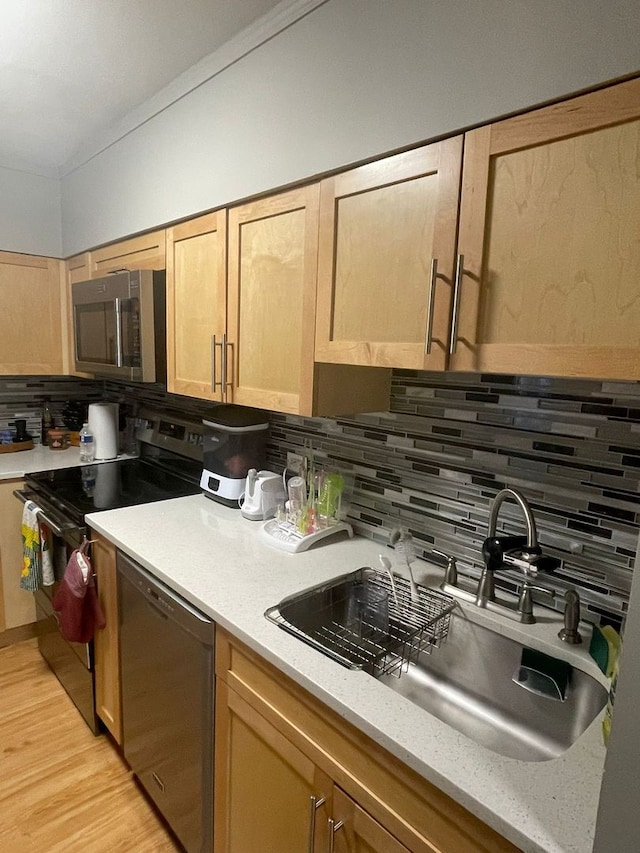 kitchen with light brown cabinetry, tasteful backsplash, stainless steel appliances, sink, and light hardwood / wood-style floors