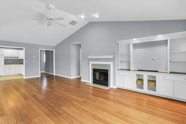 unfurnished living room featuring ceiling fan, lofted ceiling, light hardwood / wood-style flooring, and built in shelves