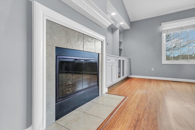 interior space featuring a tile fireplace, hardwood / wood-style floors, and built in features