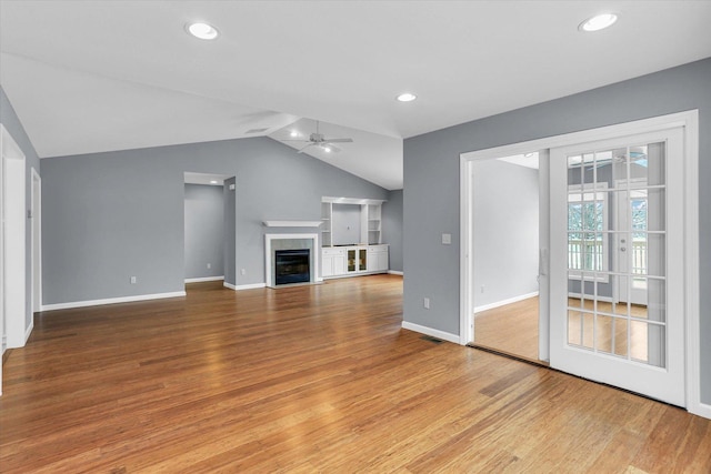 unfurnished living room featuring ceiling fan, light hardwood / wood-style floors, lofted ceiling, and a tiled fireplace