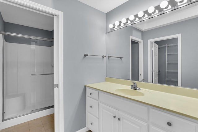 bathroom featuring a shower with door and vanity