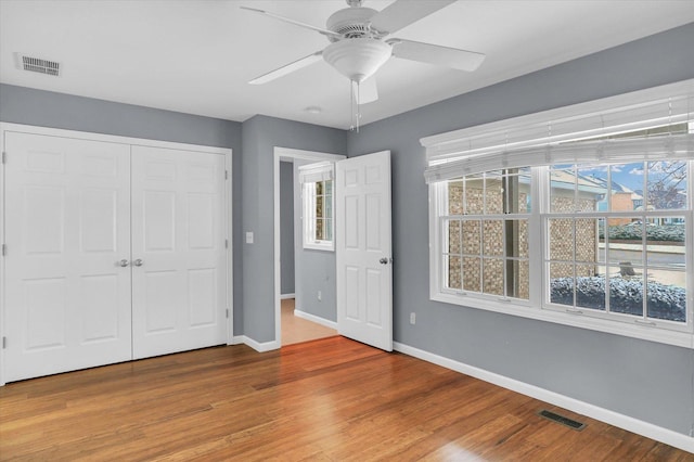 unfurnished bedroom with ceiling fan, wood-type flooring, and a closet