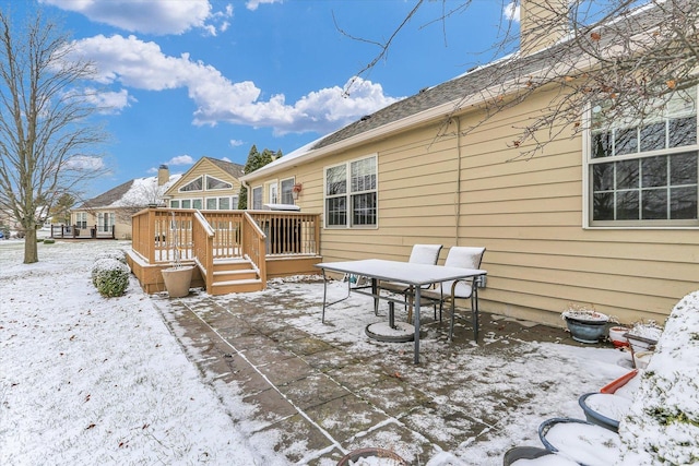 snow covered back of property with a wooden deck