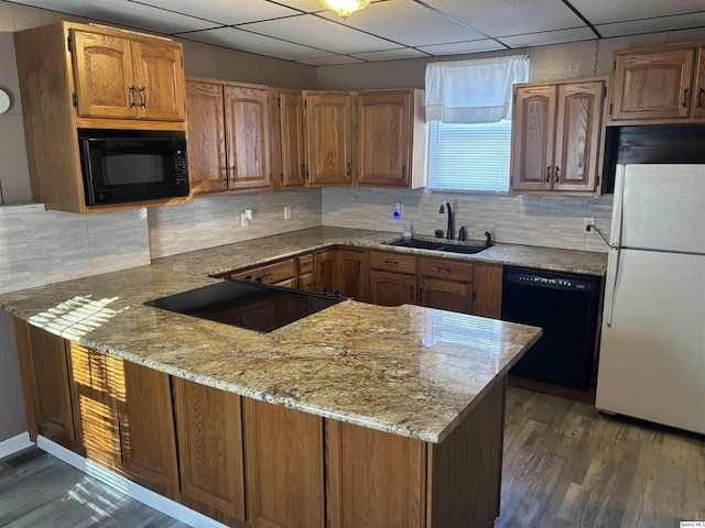 kitchen featuring light stone counters, sink, black appliances, and kitchen peninsula