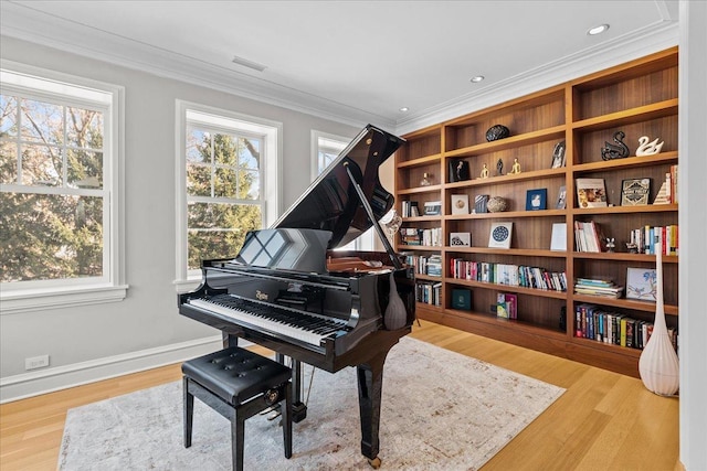 miscellaneous room with crown molding, a healthy amount of sunlight, and light hardwood / wood-style flooring