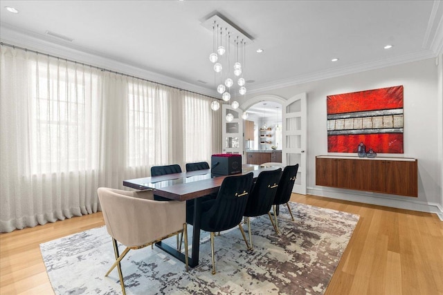 dining area with built in features, light hardwood / wood-style flooring, and ornamental molding