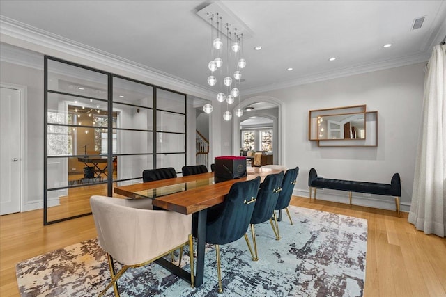 dining room with ornamental molding and light hardwood / wood-style flooring