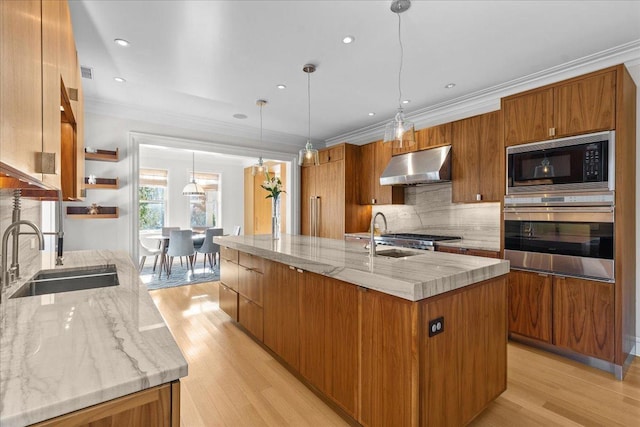 kitchen with black microwave, sink, a large island with sink, hanging light fixtures, and stainless steel oven