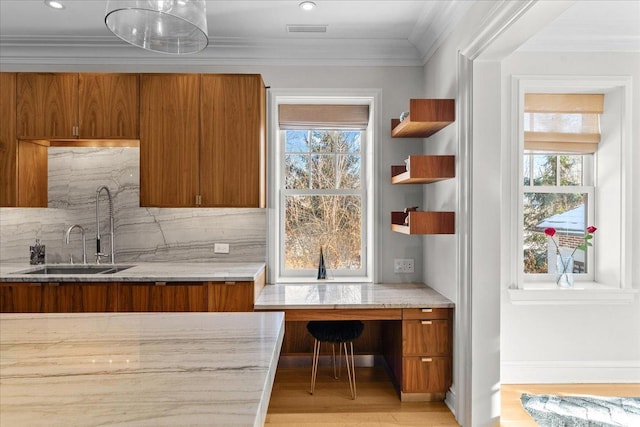 kitchen featuring ornamental molding, sink, a wealth of natural light, and light hardwood / wood-style floors