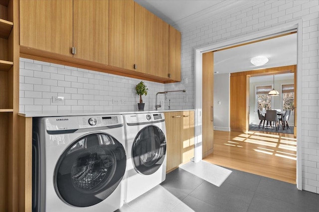 washroom featuring cabinets, washing machine and clothes dryer, crown molding, and sink