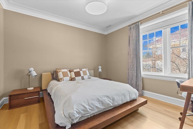 bedroom with ornamental molding and light hardwood / wood-style flooring