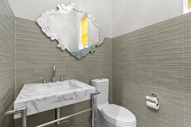 bathroom with vanity, toilet, and tile walls