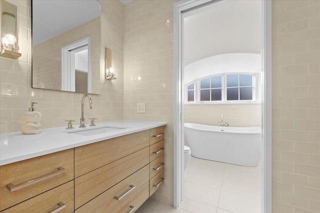 bathroom featuring a washtub, tile walls, vanity, tasteful backsplash, and tile patterned floors