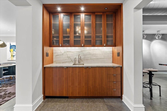 bar featuring light stone counters, sink, and decorative backsplash