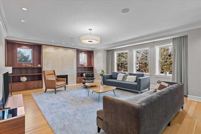 living room featuring ornamental molding, a high end fireplace, and light hardwood / wood-style floors