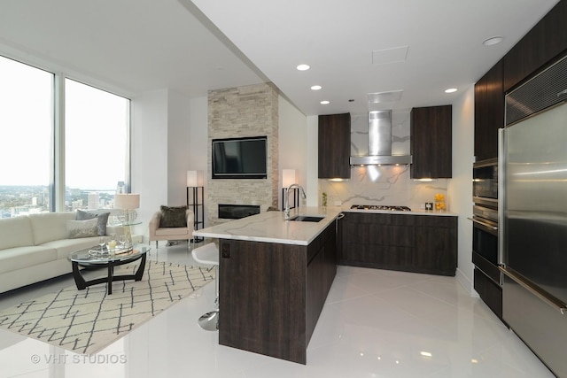 kitchen with kitchen peninsula, decorative backsplash, sink, wall chimney range hood, and a breakfast bar area