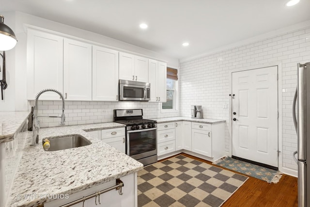 kitchen featuring white cabinetry, sink, light stone countertops, dark hardwood / wood-style floors, and appliances with stainless steel finishes