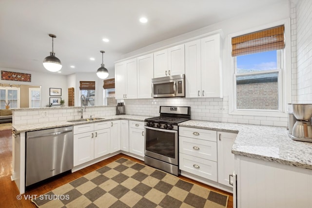 kitchen with appliances with stainless steel finishes, decorative light fixtures, and white cabinetry