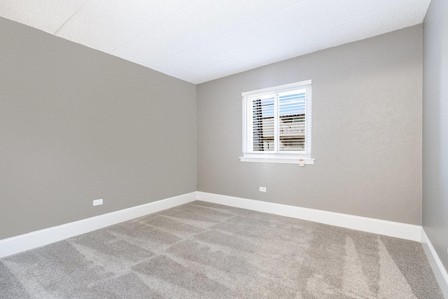 spare room featuring carpet flooring and baseboards