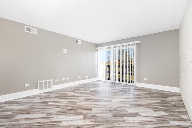 empty room with visible vents, light wood-style flooring, and baseboards