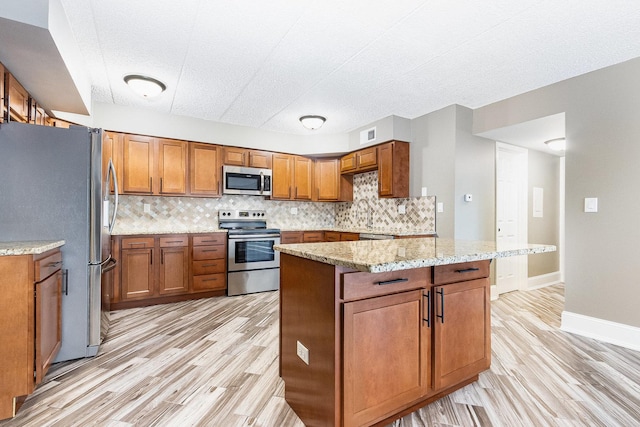 kitchen featuring appliances with stainless steel finishes, brown cabinetry, light wood finished floors, and decorative backsplash