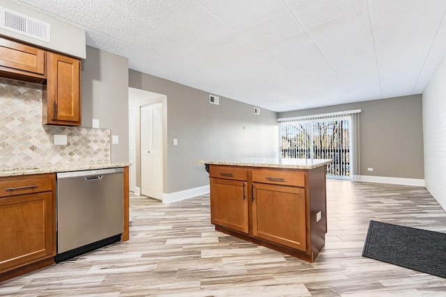 kitchen featuring light stone countertops, visible vents, brown cabinetry, and dishwasher