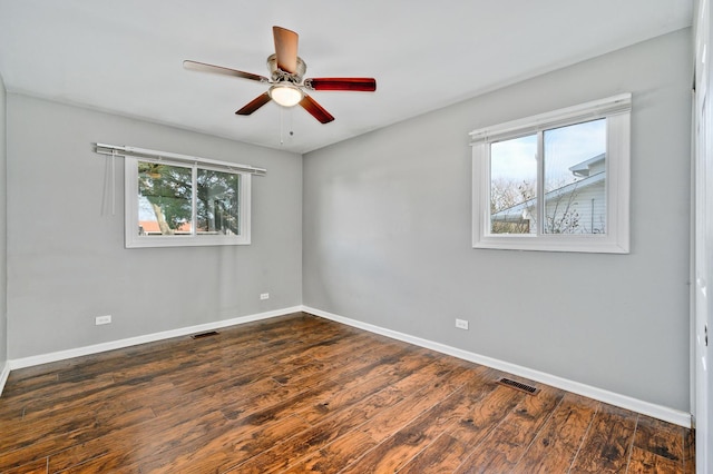 empty room with plenty of natural light, dark hardwood / wood-style floors, and ceiling fan