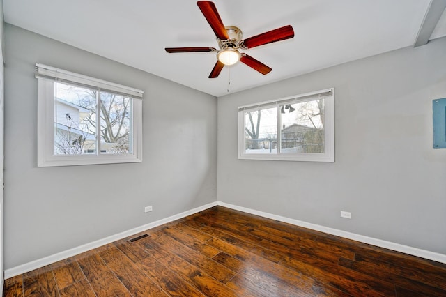 empty room with a wealth of natural light, ceiling fan, and dark wood-type flooring