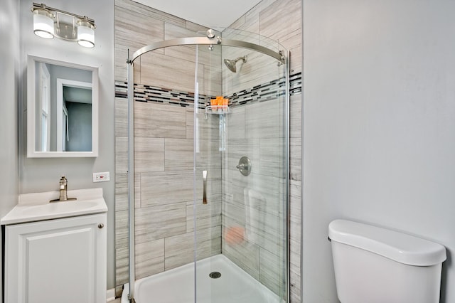 bathroom with vanity, toilet, and a shower with door