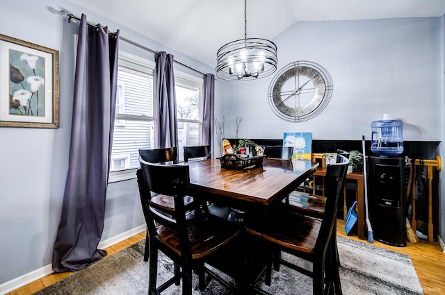 dining space featuring an inviting chandelier, wood-type flooring, and vaulted ceiling