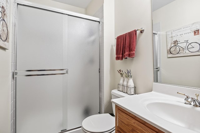 bathroom featuring a shower with door, vanity, and toilet