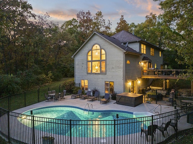 back house at dusk featuring a patio area and a swimming pool with hot tub