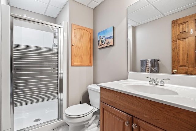 bathroom with toilet, a shower with shower door, a paneled ceiling, and vanity