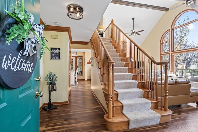 entrance foyer with ceiling fan, a towering ceiling, dark hardwood / wood-style floors, and beam ceiling