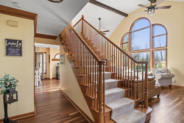 staircase featuring a high ceiling, hardwood / wood-style floors, ceiling fan, and beam ceiling