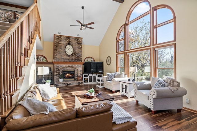 living room with dark hardwood / wood-style floors, high vaulted ceiling, beam ceiling, a fireplace, and ceiling fan