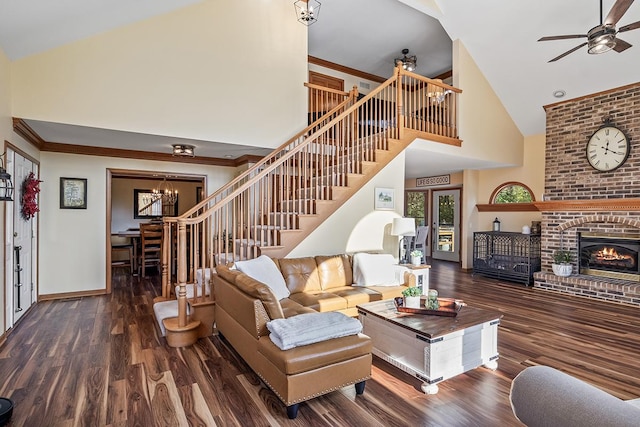 living room with dark wood-type flooring, high vaulted ceiling, ceiling fan with notable chandelier, and a fireplace