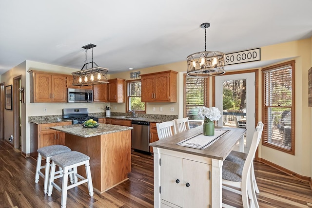 kitchen with dark wood-type flooring, a center island, stainless steel appliances, an inviting chandelier, and sink