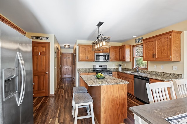 kitchen with dark wood-type flooring, pendant lighting, a center island, stainless steel appliances, and sink