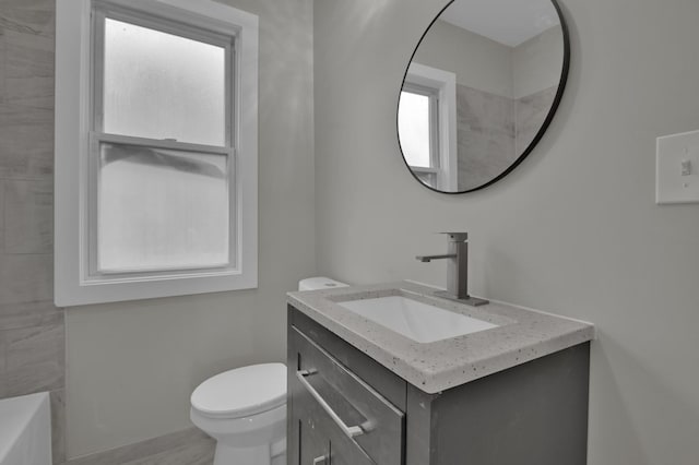 bathroom featuring vanity, a bath, and toilet