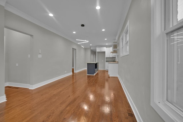 unfurnished living room featuring hardwood / wood-style floors, ornamental molding, and sink